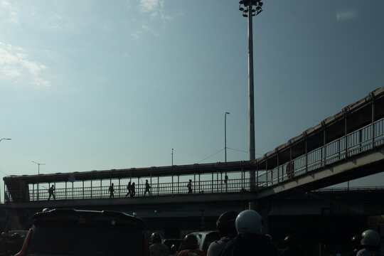 Silhouette of Pedestrians Walking on an Overpass Bridge Against Clear Sky in Jakarta, Indonesia
