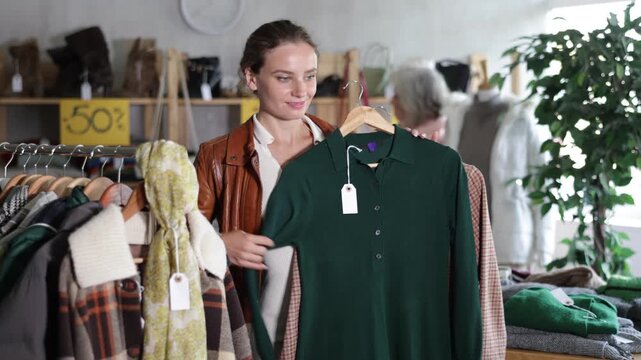 Adult woman chooses a warm wool dress for the winter season, she carefully examines the fabric before buying