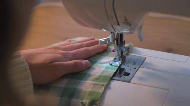 Woman sewing on a sewing machine. Over the shoulder shot.