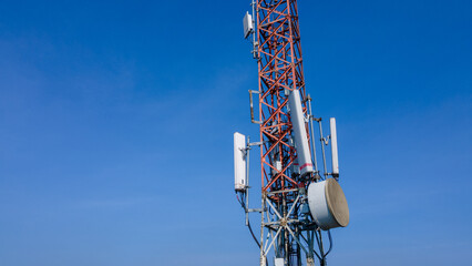 Naklejka premium Radio Mast on Cellular Telecommunications Tower in Daylight with Blue Sky
