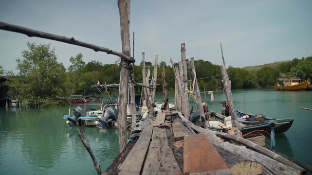 Person walking on a rustic wooden fishing jetty in southeast asia