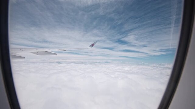 A view from an airplane window reveals an expansive cloudscape and wing against a textured sky. Perfect for travel-related content or aviation themes.