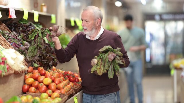 Elderly man buyer choosing fresh beets in vegetable shop