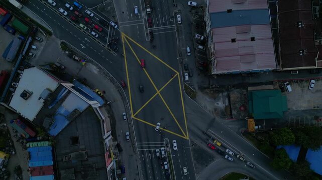 vertical bird's eye view, cars and motorbikes driving through a yellow marked box junction in Port Klang, Malaysia. Lovely aerial view drone top down Above view