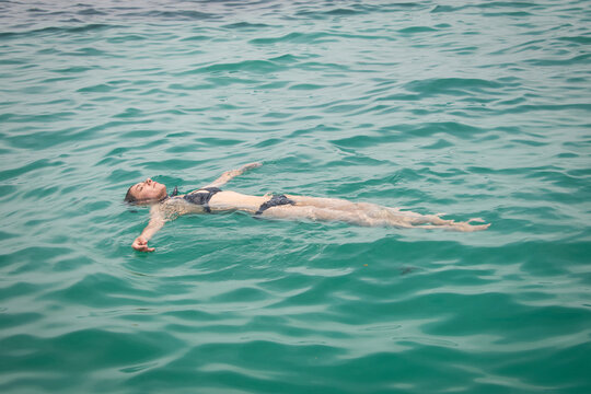 woman in bathing suit floating and relaxing on back in water