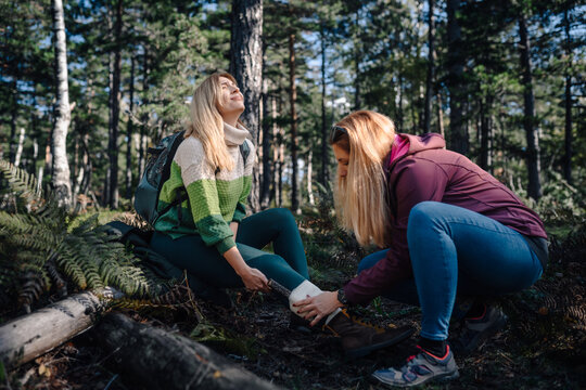 Friend providing first aid for hiker injured ankle