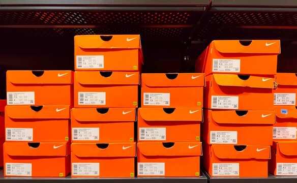 Photo of neatly stacked Nike shoe boxes on retail store shelves, showcasing organized footwear inventory with the iconic orange Nike packaging.
