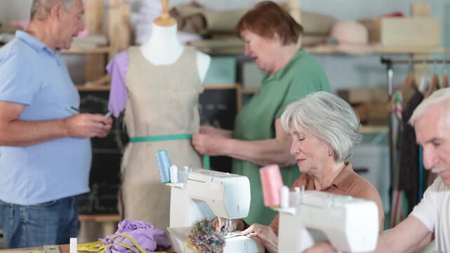 Group of elderly men and women sew and work with mannequin during master class