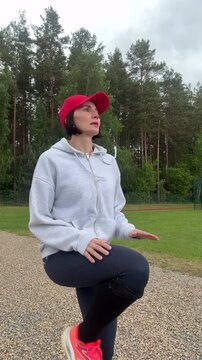 Side view of athletic female in sportswear practicing mindful movement and balance workout on gravel path against green trees