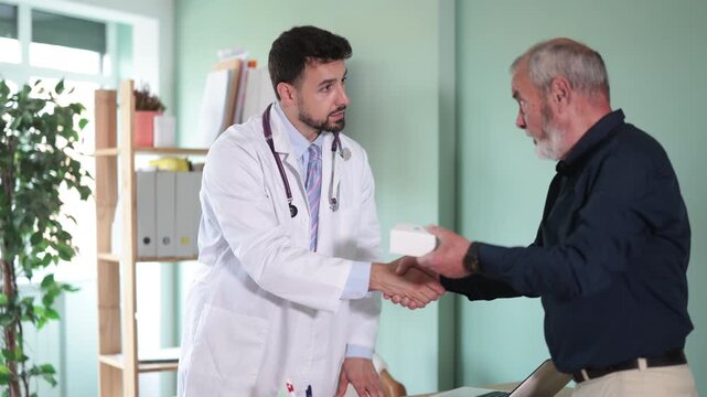 Successful medical appointment, male doctor and senior man patient shake hands. Clinic, medical appointment, doctors visit, medical consultation, treatment and prevention of diseases