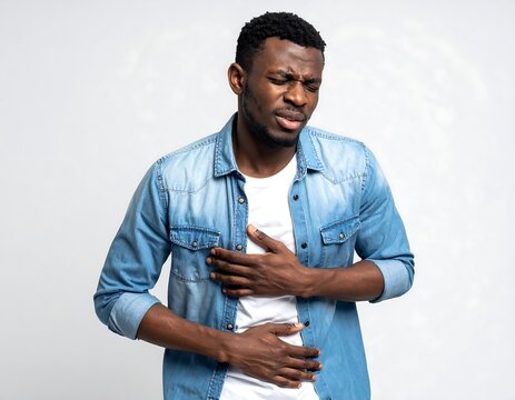 Young African Man Holding Chest and Stomach in Pain Against Gray Studio Background