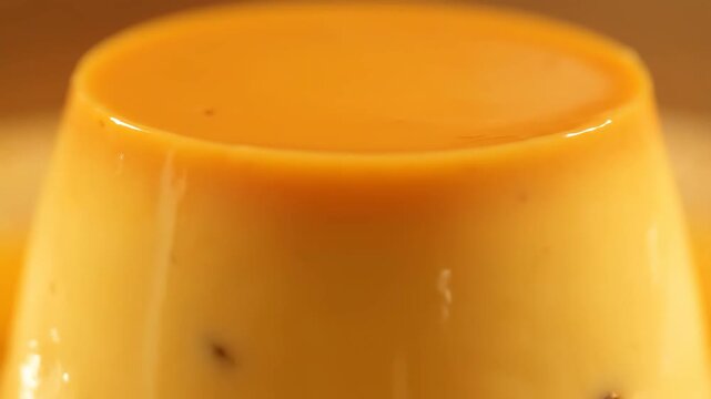 Macro view of smooth, glossy cr&egrave;me caramel dessert, showing the rich texture and golden color of the custard and caramel glaze