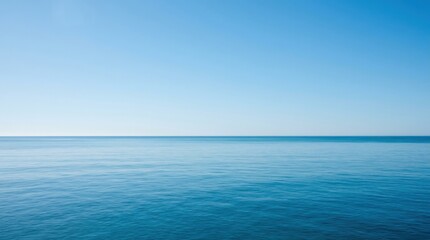 Fototapeta premium Endless blue sea meeting clear sky at horizon. Calm ocean water surface for World Oceans Day. Tranquil nature background for relaxation, travel, vacation, environment conservation concept.