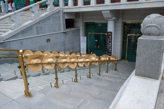 Yangsan, Gyeongsangnam-do, South Korea - May 15 2026: Straw hats used by templestay participants placed in a neat row on the handrail of stone stairs at Tongdosa Temple