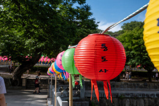 Yangsan, Gyeongsangnam-do, South Korea - May 15 2026: A close up of a red paper lantern with the Korean text Tongdosa written on it hanging with other colorful lanterns at the temple entrance