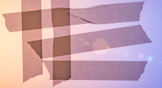 Intersecting stripes of semi transparent adhesive tape on gradient background.