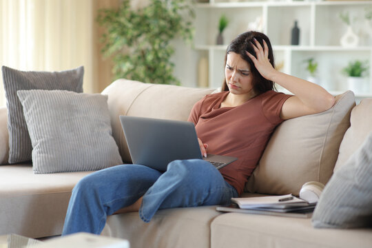 Worried young student checking bad news on laptop