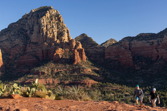Two men hiking up a red rock desert trail