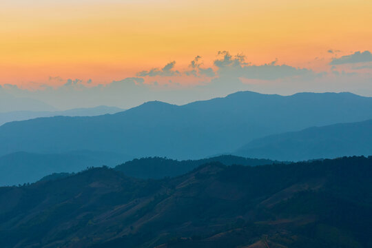 Mountain range at sunset with layers of blue and orange sky