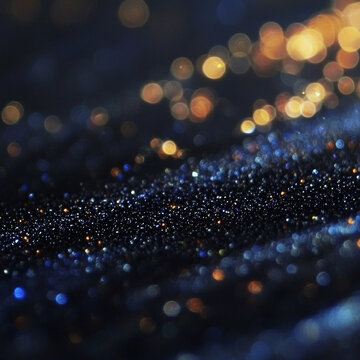 Dark surface shimmering with blue, silver, and gold glitter particles in focus, with soft, blurred golden and blue bokeh lights above