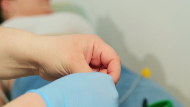 Hand stretches medical glove before procedure on patient. Specialist prepares protective equipment ensuring hygiene during examination