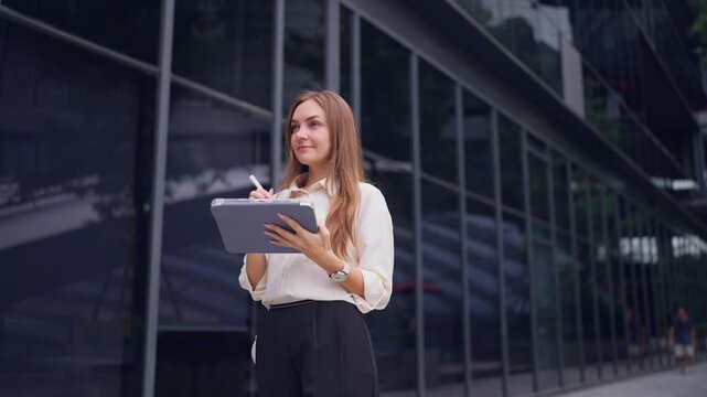 Caucasian young businesswoman using digital tablet outside the office. 