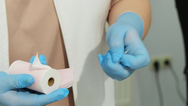 Healthcare worker unwraps paper roll before placing into medical device. Nurse removes package preparing recording paper for diagnostic test