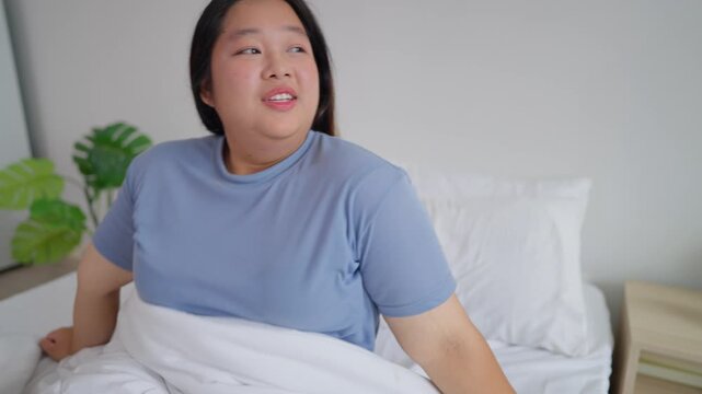 Asian plus-size woman in pajamas wake up in the morning with happiness. 