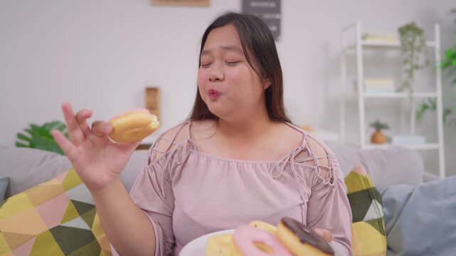 Asian plus-size woman enjoy eat favorite donut while relaxing at home. 