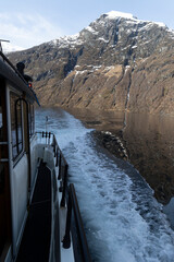 Fototapeta premium A nice boat tur in the fjord near Geiranger with passengers. Winter scenery in Geirangerfjord, Sunnmore region, Norway.