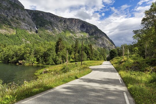 Single-lane country road through valley, river Aura, typical landscape with high mountains in summer, Eikesdal, Eikesdalen, Molde, More og Romdal, Norway