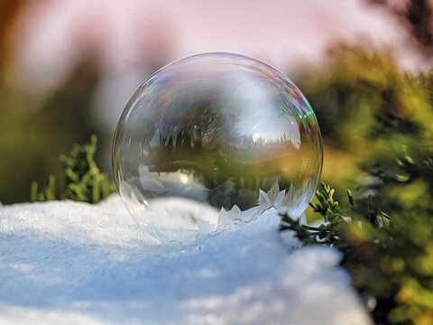 Freezing soap bubble with ice crystals on snow, stylised oil painting