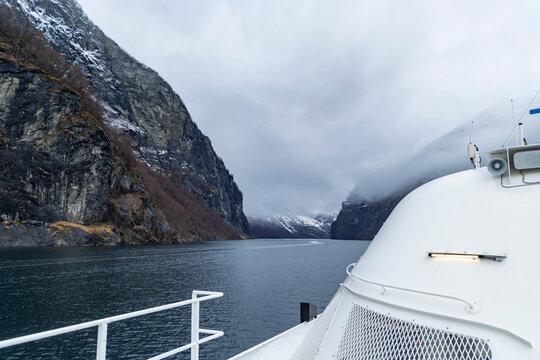 A beautiful winter cruise day on an electric tour ferry with deck details in foreground.. Winter scenery in Geirangerfjord, Sunnmore region, Norway.