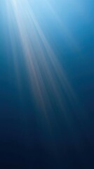 Obraz premium Sunlight rays piercing through deep blue ocean water. Underwater view of light beams in sea. Concept of nature, environment and World Oceans Day. Tranquil marine background texture.