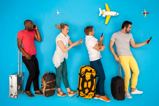 People queuing at the airport, using their mobile phones