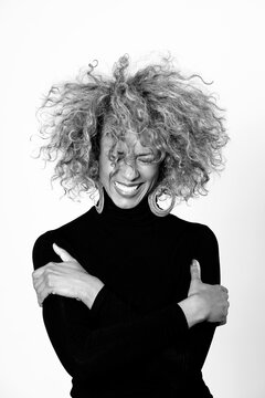 Portrait of laughing woman with afro wearing black turtleneck pullover