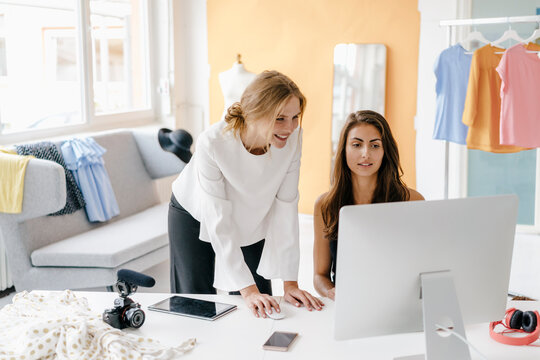 Two young women in fashion studio with camera and computer