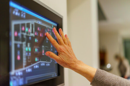 Senior woman's hand touching display panel of domestic technology