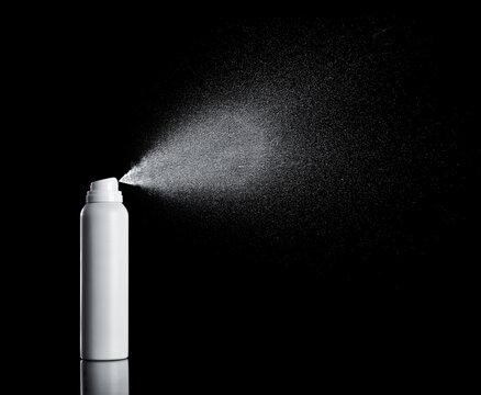 White spraying aerosol can in front of black background