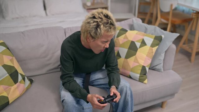 Asian young man gamer playing console game in cozy living room at home. 