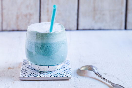 Glass of blue coloured latte with spirulina algae, vegan plant milk, ginger and rice syrup