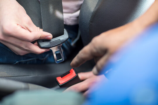 Male hands in car fastening safety belt