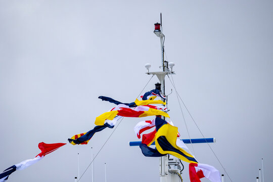 An empty upper deck of a tour ferry in fjords with nautical flags blowing in the wind. Winter scenery in Geirangerfjord, Sunnmore region, Norway.