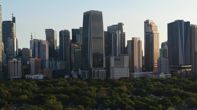 Aerial parallax of the sunlit Makati skyline in Manila, golden hour in Philippines