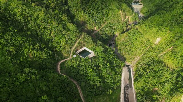 Aerial view of a hillside watershed in Catanduanes, Philippines, amid lush tropical mountains, access roads, and dense island greenery