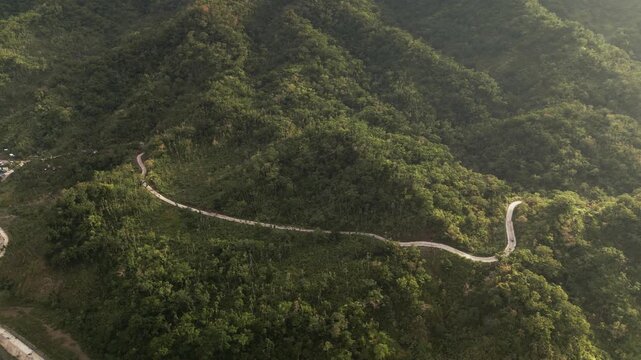 Aerial view of a winding mountainside road in Caramoran, Catanduanes, cutting through lush tropical hills and dense island greenery