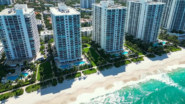 Aerial view of luxurious beachfront high-rise condominiums with swimming pools on a sunny day