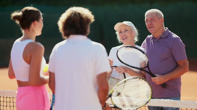 Group of friends or family spending time playing sports on tennis courts and friendly talking during breaks