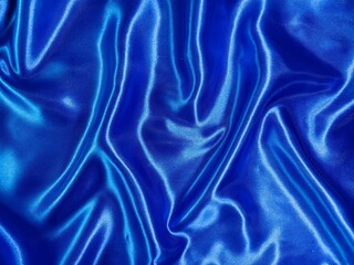 Fototapeta premium Luxurious royal blue satin fabric shimmers with elegant folds, creating a rich and sophisticated abstract texture.