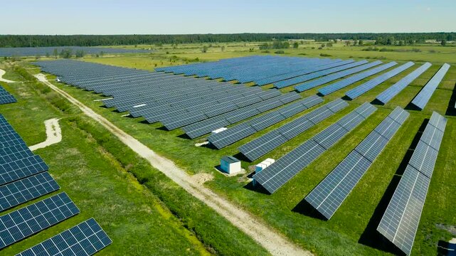 Drone flying over a large solar farm with photovoltaic panels generating clean, renewable energy in a lush green field on a sunny day, showcasing sustainable technology and green power production